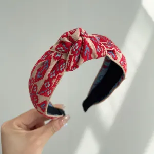 Primer plano de una diadema con nudo de estilo bohemio y patrones étnicos rojos.