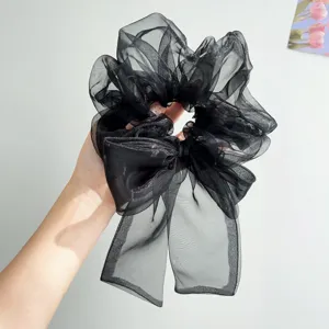 Detailansicht eines schwarzen Organza-Haargummis mit großer Schleife und Glanzeffekt