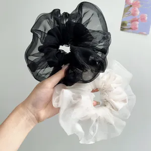 Detailansicht von schimmernden Organza-Haargummis in Schwarz und Cremeweiß mit Glanz