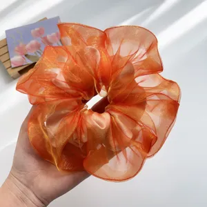 Detailaufnahme eines schimmernden orangefarbenen Organza-Haargummis mit Falten