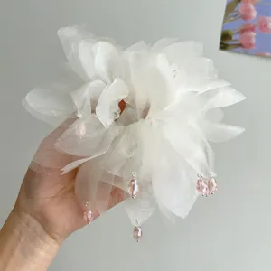 Dettaglio di un elegante elastico in organza bianca con perline di cristallo rosa