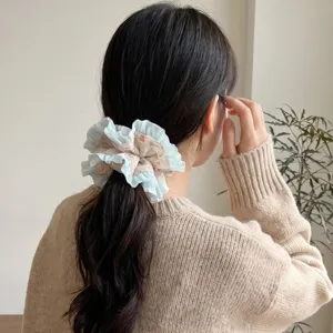 Detailed view of a sweet candy-colored pleated ruffle mesh scrunchie worn on dark hair