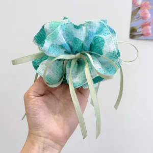 Close-up of Mori style floral print scrunchie hair tie with elegant green ribbons