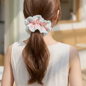 Close-up of a floral pleated scrunchie with blue ruffles worn on a ponytail.