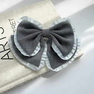 Detailansicht der Textur einer grauen Stoffschleife mit hellblauem Rüschenrand.