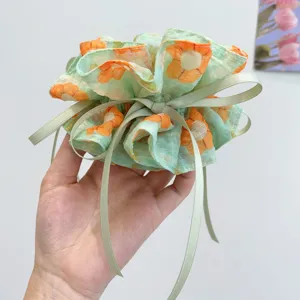 Macro detail view of a soft green floral print scrunchie with an elegant ribbon bow.