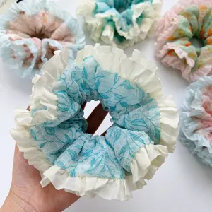 Close-up of a blue and white ruffled mesh scrunchie with floral print pattern
