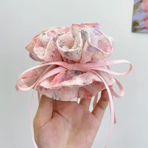 Close-up detail of a pink floral print scrunchie with long ribbon bow for hair styling