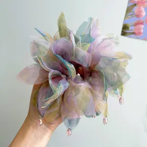 Dettaglio di un elastico per capelli floreale in organza color pastello con perline pendenti