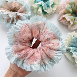 Close-up detail of sweet pleated mesh scrunchie with floral print and ruffle edges