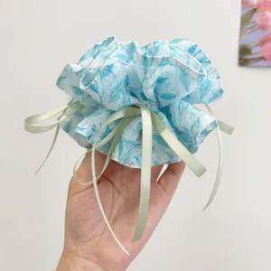 A close-up view of a floral blue scrunchie featuring elegant light green ribbons