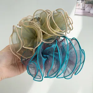 Detail of ruffled organza hair shark clips in champagne and blue gradient