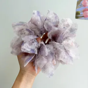 Dettaglio dell'elastico per capelli in organza lilla con ciondoli in cristallo