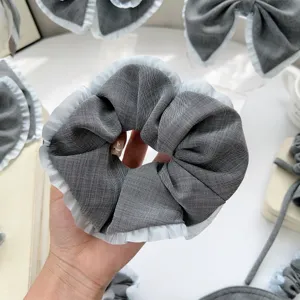 Detailaufnahme eines grauen Haargummis mit eleganten weißen Faltenrüschenkanten