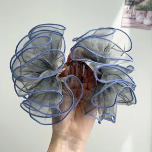 Close-up view of a large grey mesh hair claw clip with blue stitched edges and ruffles