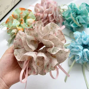 Detailed view of a soft floral print scrunchie featuring elegant pastel pink ribbon accents