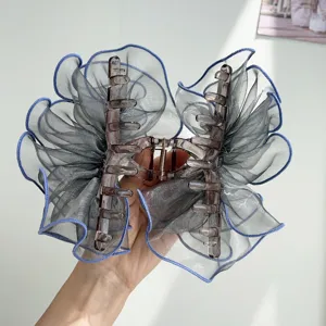 Detailed view of an elegant grey organza mesh bow hair claw clip with blue piping edges.