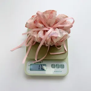 Detailed view of floral print hair scrunchie with ribbons weighing 17.6g on scale.