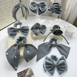 Detailansicht eines grauen karierten Haarschmuck-Sets mit Rüschen und Schleifen.