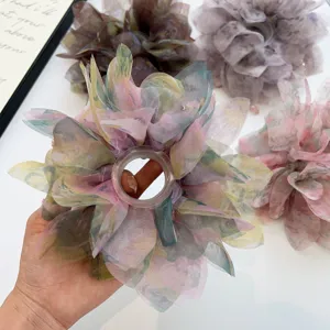 Vista dettagliata di un elastico per capelli in organza trasparente colorata in mano