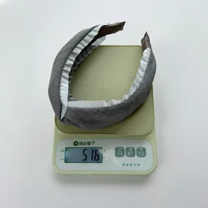 Detailansicht eines gefalteten grauen Stoff-Stirnbands mit 51,6 g Gewicht auf einer Waage.