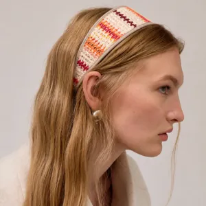 Vue détaillée d'un serre-tête en paille tressée avec des motifs à ondes colorées de profil.