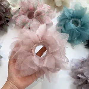 Dettaglio di un elastico per capelli a fiore in organza rosa con accenti di perline.