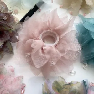 Dettaglio di un elastico per capelli in rete rosa a strati con piccoli ciondoli a perla