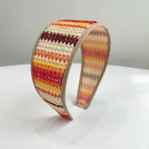 Détail d'un large serre-tête en paille tressée à rayures colorées style bohème