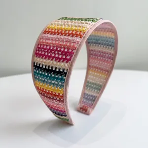 Détail d'un serre-tête en paille tressée colorée avec des rayures horizontales