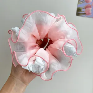 Nahaufnahme des rosa und blauen Rüschen-Haargummis aus Netzgewebe mit Stickerei