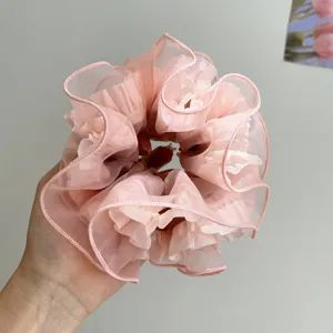 Nahaufnahme der zarten Faltenstruktur eines großen rosa Mesh-Haargummis