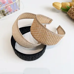 Vue détaillée de trois serre-têtes larges tressés en paille en beige et noir.