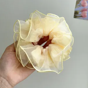 Nahaufnahme von hellgelbem Mesh-Haargummi mit weicher Organza-Textur