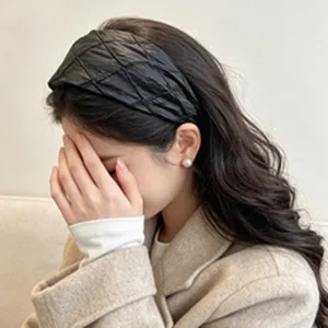 Macro view of a stylish black quilted wide headband worn by a woman in a beige coat.