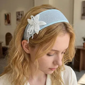 Detail shot of a blue vintage wide mesh headband with white beaded floral charm