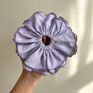 Vista detallada de un coletero gigante morado con textura de tela suave plisada en capas