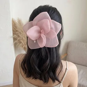 Detail of a pink mesh flower hair clip worn on a woman's dark hair.