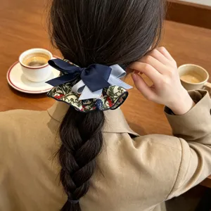 Detailed view of the elegant floral scrunchie with navy blue bow on braided hair