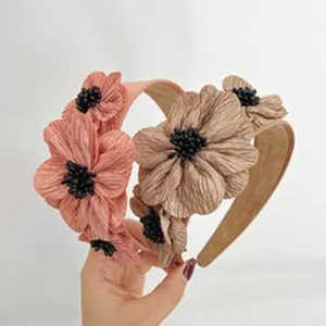 Detailed view of elegant fabric flower wide headbands in coral and beige color options.