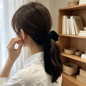 Close-up detail of an elegant black velvet bow hair tie with long hanging ribbons