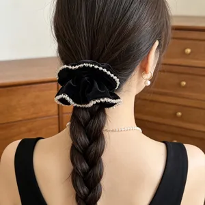 Nahaufnahme eines schwarzen Samt-Scrunchies mit Kristallperlen an einer Flechtfrisur