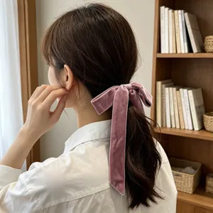 Detailed macro shot of an elegant pink velvet bow ribbon hair tie on a ponytail.