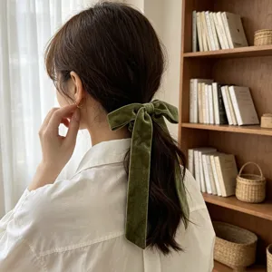 Close-up detail of an elegant olive green velvet bow hair tie with long hanging ribbons