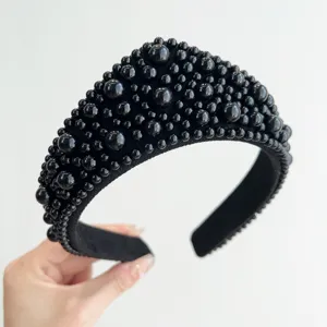 Primo piano di un cerchietto nero con decorazioni di perle in stile vintage chic.