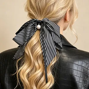 Detail eines schwarz-weiß gestreiften Haargummis mit Schleife und Perle auf blondem Haar