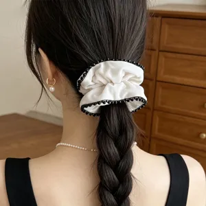 Detailansicht eines eleganten weißen Samt-Haargummis mit schwarzen Perlen im Haar