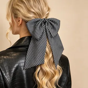 Detailansicht einer großen schwarz-weiß gestreiften Schleife auf blondem Haar