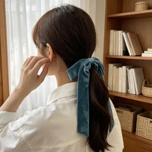 Blue velvet bow hair tie with long streamers shown in a detail hair styling shot.