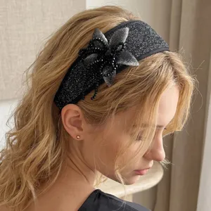 Detailed side view of an elegant wide black hand-beaded flower headband on a model